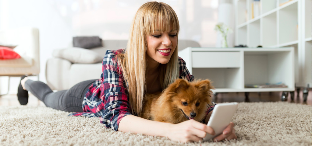 A young woman and her Pomeranian looking at a mobile phone screen